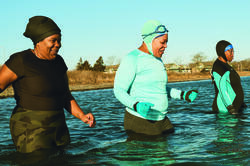 three Black women wade into the sea