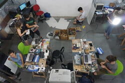 several students at workstations topped with an array of computing hardware