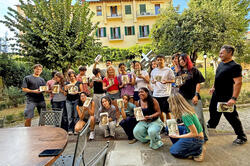 a group of students holds their paintings ourside in italy