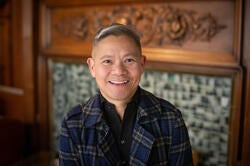 man smiling in front of fireplace