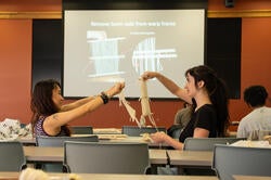 two students hold up small looms