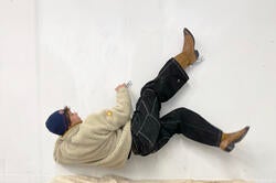 a student hangs off a wall in a performance piece using steel handles