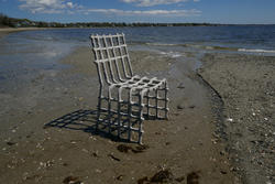 A chair with open spaces sits on a beach