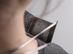 A person is wearing a metal necklace made up of three interlocking pieces.