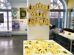 yellow pieces of paper, each featuring a single black letter, spell out "Collect made public" on a pillar inside a study spaceout "