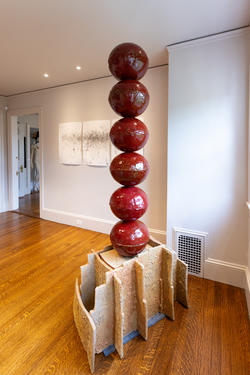 six red spheres stacked atop one another, all atop a small sculptural platform