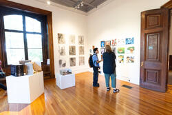 Two people view art work in a gallery