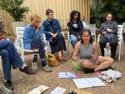 students sit outside and discuss their work