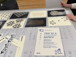 several works on paper with variety of text, shapes and digital illustrations in white, blue, black and gold