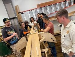 several people in a studio work on a wood construction project