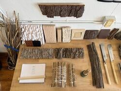 a desk covered with carefully arranged wood objects of various shapes and types, as well as cutting tools