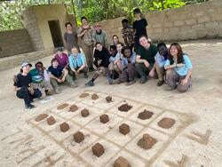 students smile for a photo behind a piece of art