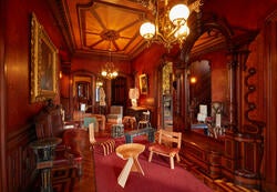 Assortment of furniture including chairs and tables set in an opulent room with red walls and warm lighting