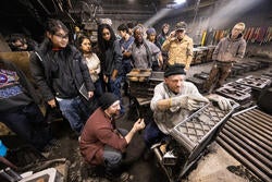 a group views a cast iron demonstration at a foundry