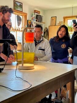 several people gathered around a table looking at a lamplit object