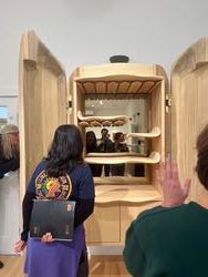 students look inside an open wooden cabinet