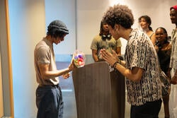 two people stand talking to each other, one holds flowers