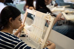 a person weaves on a loom