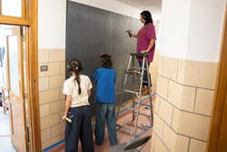 student hammer chicken wire into a wall mural