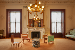 Contemporary furniture pieces arranged in the center of an opulent traditional parlor room