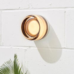 Dimple wall sconce hung on a concrete wall above a green plant