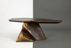an unevenly shaped steel table, mostly dark brown with patches of gold