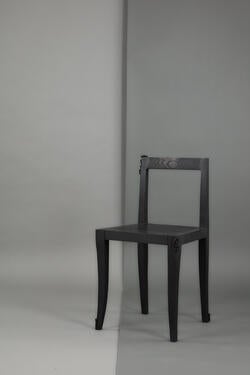 a minimalist chair made from dark wood