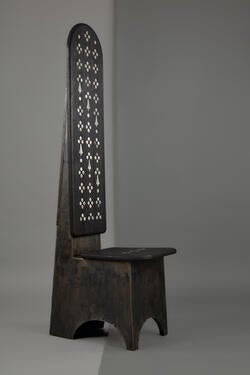 a dark wood chair with a tall, ornately patterned back