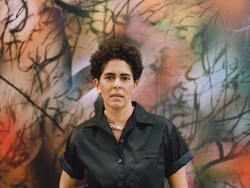 Julie Mehretu stands in front of one of her paintings