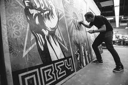 black-and-white image of Fairey using a brush on a large piece