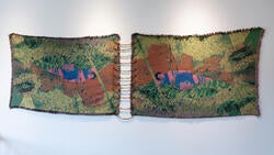 two woven, wall-mounted textiles featuring a pink-and-blue human shape lying in a green space