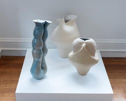 three ceramic vessels stand on a gallery podium