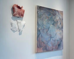 a sculptural work and painting hang side by side on a gallery wall