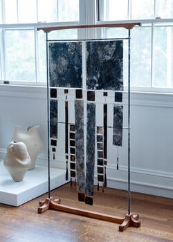 dozens of square paper surfaces hang from the frame of a Japanese screen