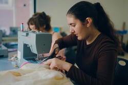 a teenage student at work on a sewing machine