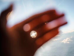a hand held up against the ocean in sunlight