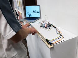 a student interacts with a laptop-connected device sitting atop an exhibition podium