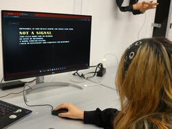 a student manipulates a mouse while looking at a monitor that reads "Not a signal" in large letters