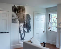 a charcoal illustration of an angelic figure, drawn on multiple pieces of paper, mounted on a gallery wall among other art objects