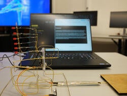 arrangement of yellow wire hooked into a small device in front of an open laptop