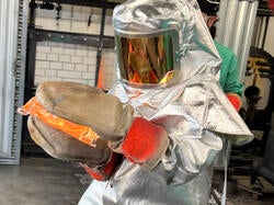 a student wearing a heat-protection suit rushes a hot piece to the annealing oven
