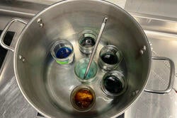 inside the large pot, the dye baths are brought up to temperature with a thermometer for precise  control