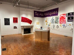 graphic design prints pinned on gallery walls surrounding a podium displaying smaller print pieces