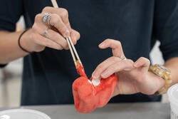 a student paints a pepper-shaped rattle with a bright red glaze