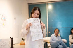 a student holds up a sketch