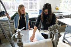 faculty member Megan Foster works with a student in printmaking studio