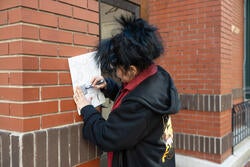 student sketching against brick wall