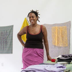 Joanna Booth standing in front of prints pinned to a studio wall
