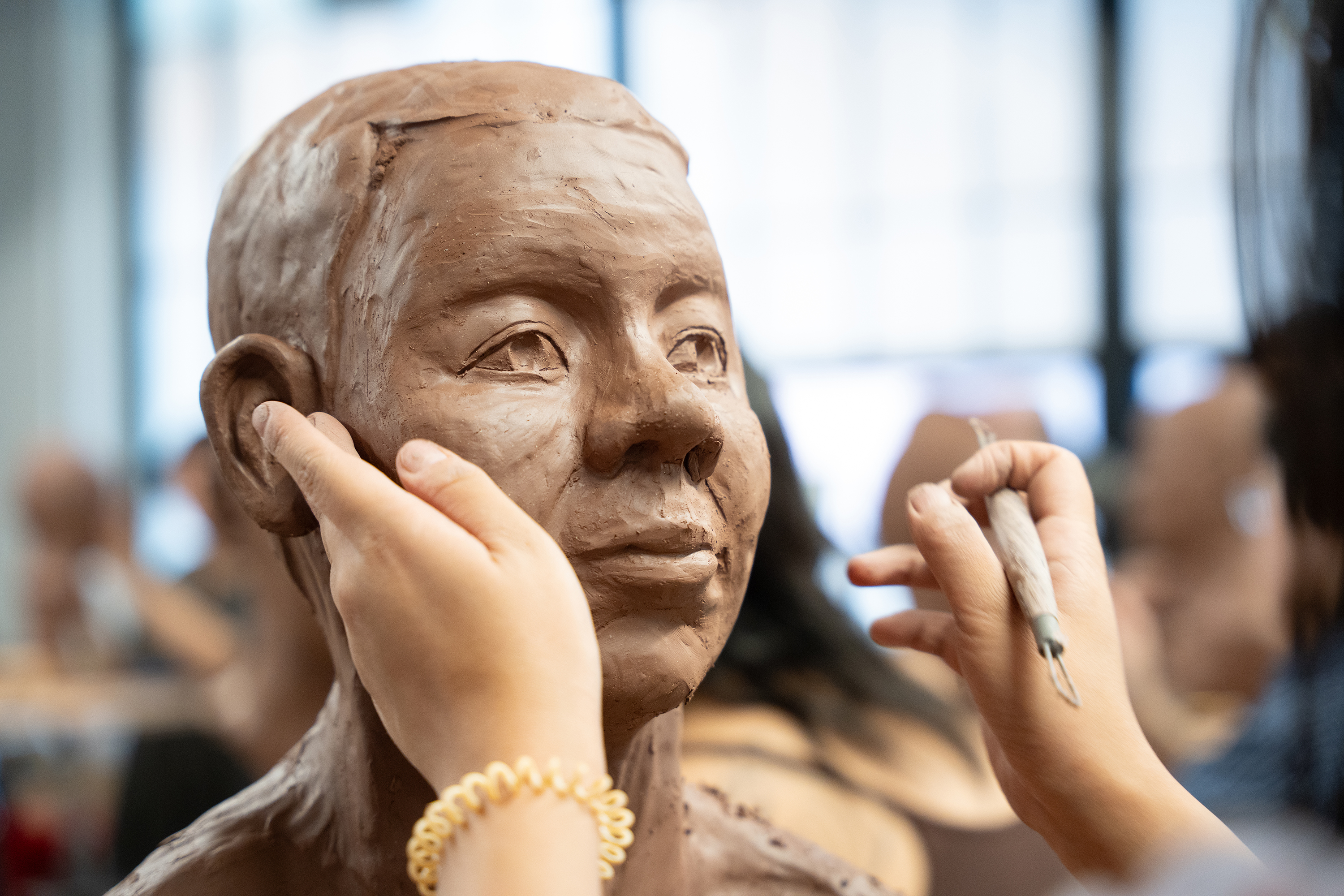 hands shaping a clay head