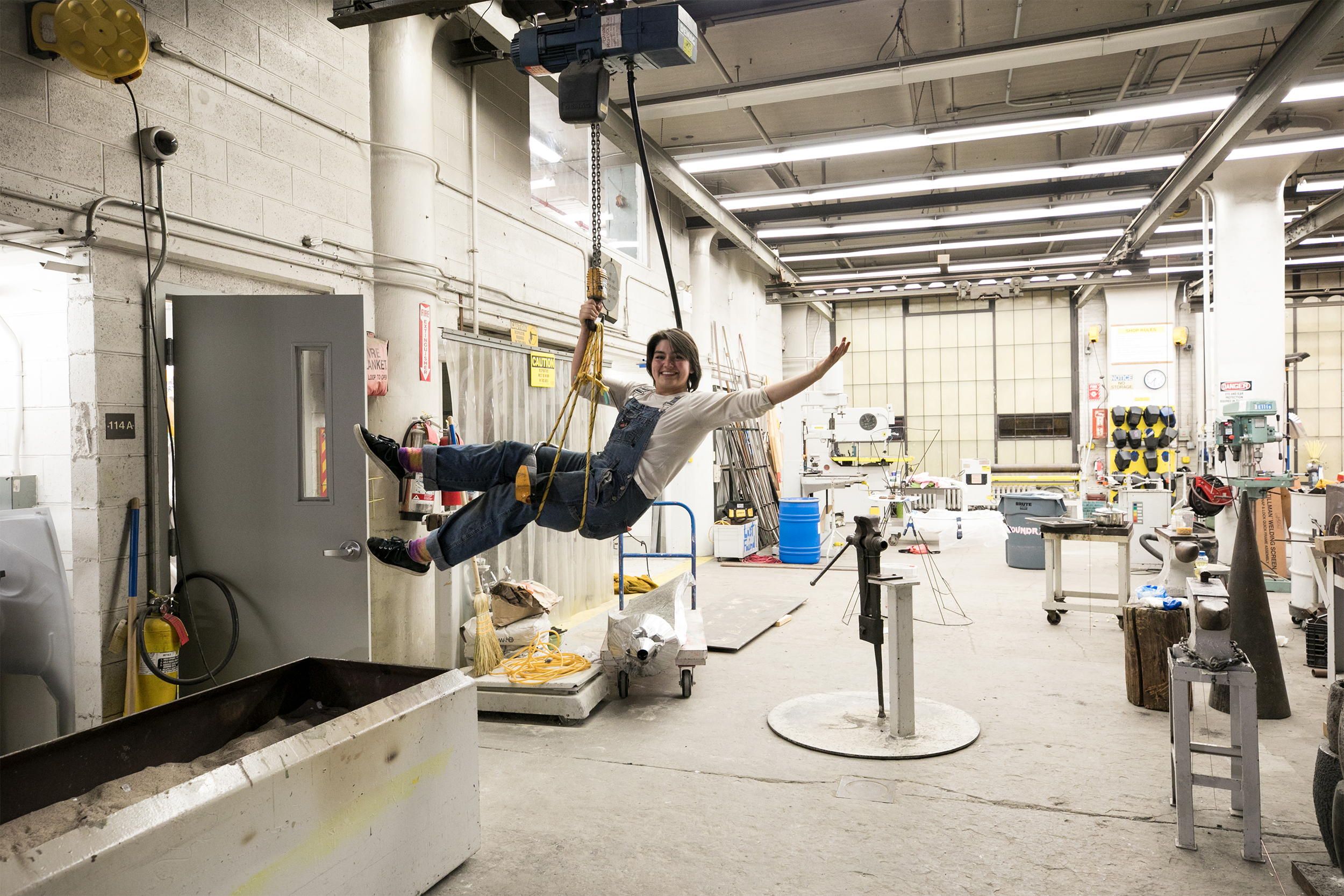 smiling student hangs from a harness inside the Metcalf Building